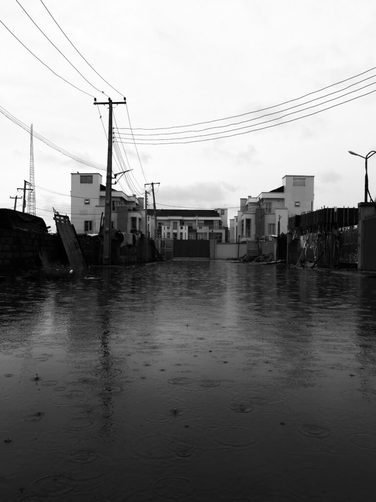 A flooded Nigerian street with residential buildings and power lines showing the urgent need for climate health early warning systems in Nigeria