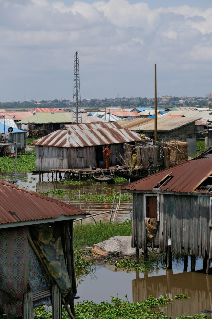 Flooded residential area in Lagos with homes surrounded by water, highlighting climate risks increasing insurance costs and affecting housing affordability in Nigeria