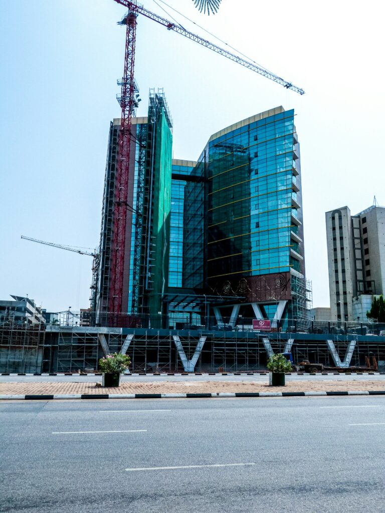 A modern high-rise building under construction in Nigeria with cranes and glass facade, representing real estate development and housing finance growth.
