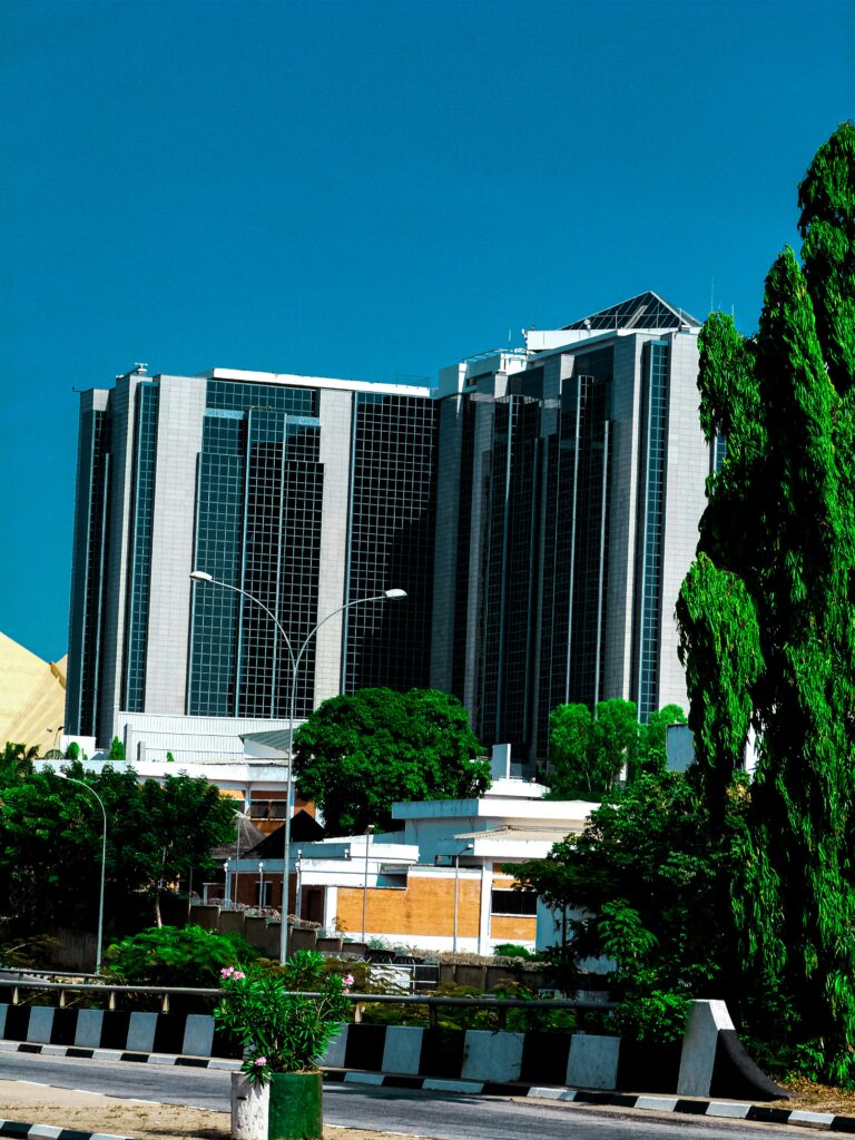 A modern glass commercial building in Abuja Nigeria surrounded by green trees representing the rise of green certified buildings earning higher rents across Africa